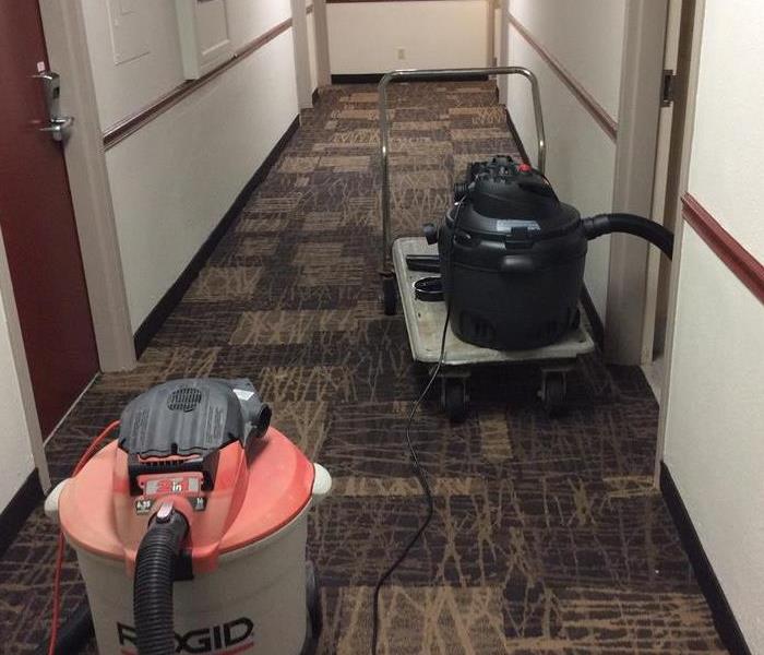 A hotel hallway where sewage has soaked into the carpet tiles and drywall