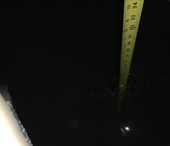 A measuring tape is pushed into the water showing the water to be nearly 2 feet high