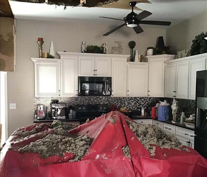A kitchen island is covered by collapsed drywall and insulation after a fire
